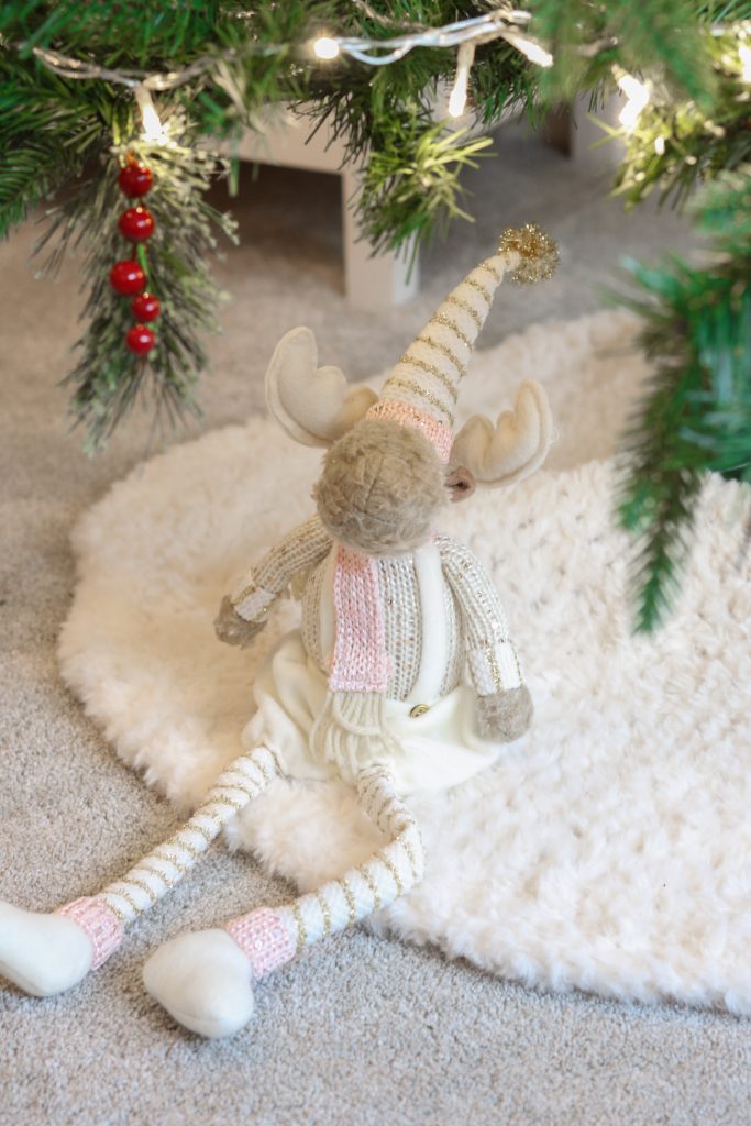 crochet tree skirt made in cream yarn with a cream, pink and beige reindeer teddy sat on it under the Christmas tree