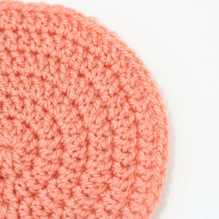 a flat lay image of a crochet flat circle made in orange yarn on a white background
