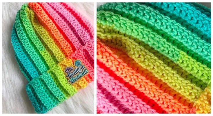 A rainbow-coloured crochet beanie sits on a white background