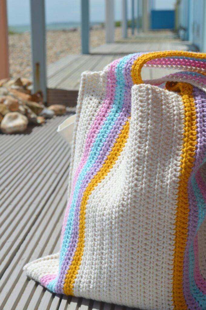 striped crochet beach bag with the beach in the background