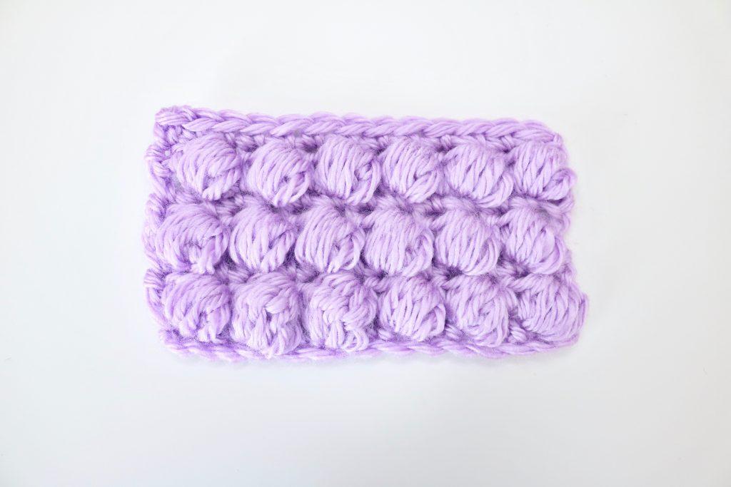 A swatch of puff stitch in lilac yarn is shown against a white background.