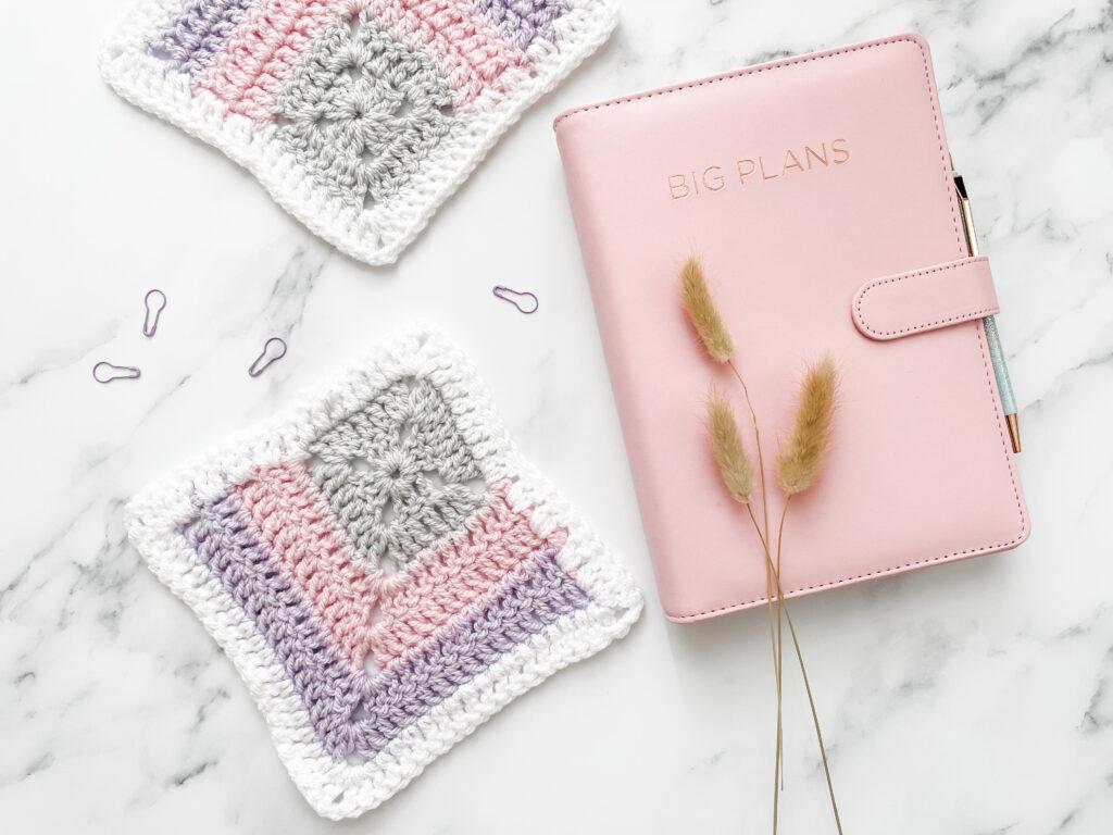 Solid mitered granny square with a pink planner on a marble background.