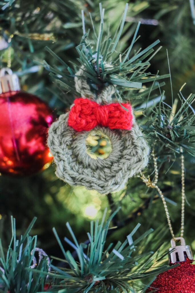 mini crochet wreath in green yarn hanging from a decorated Christmas tree