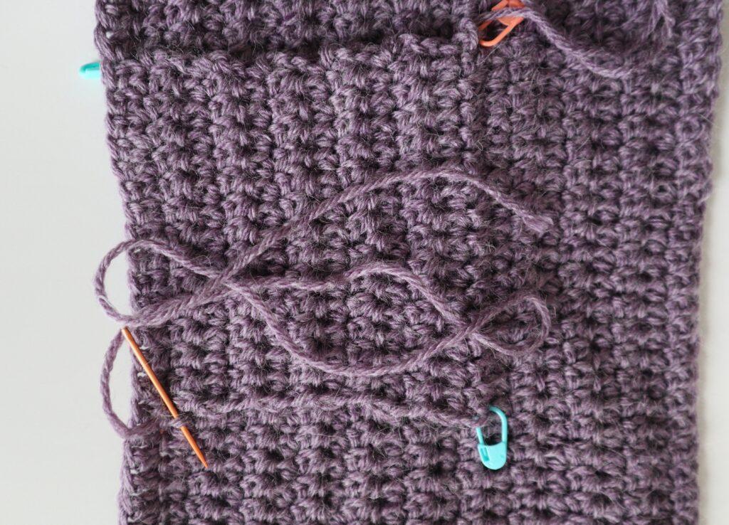 A swatch in purple yarn showing the construction of the crochet cardigan