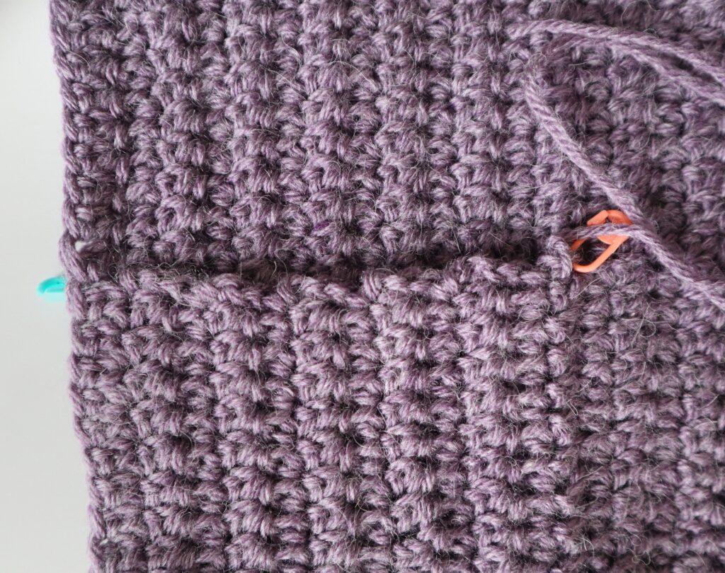 A swatch in purple yarn showing the construction of the crochet cardigan