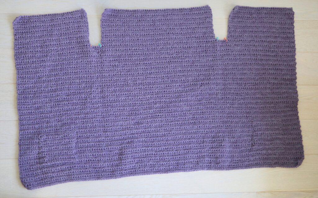 A swatch in purple yarn showing the construction of the crochet cardigan