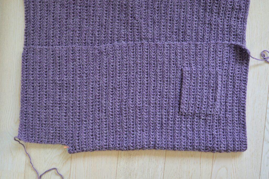 A swatch in purple yarn showing the construction of the crochet cardigan