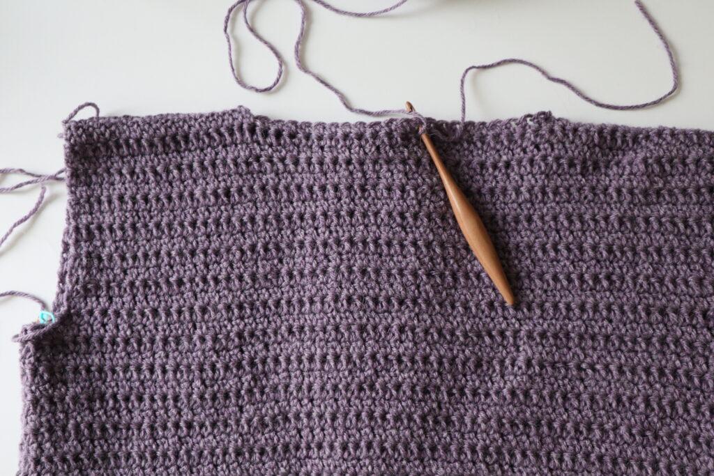 A swatch in purple yarn showing the construction of the crochet cardigan