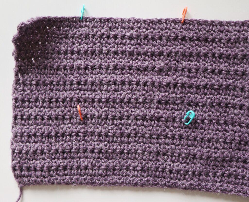 A swatch in purple yarn showing the construction of the crochet cardigan