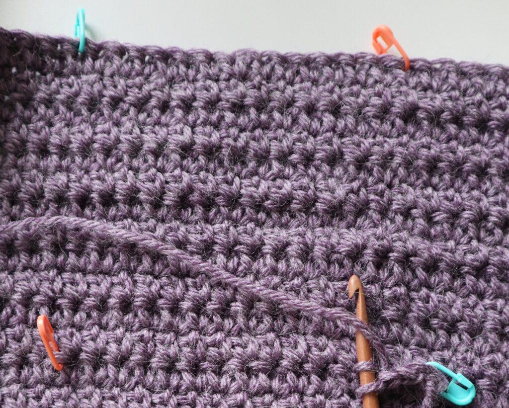 A swatch in purple yarn showing the construction of the crochet cardigan