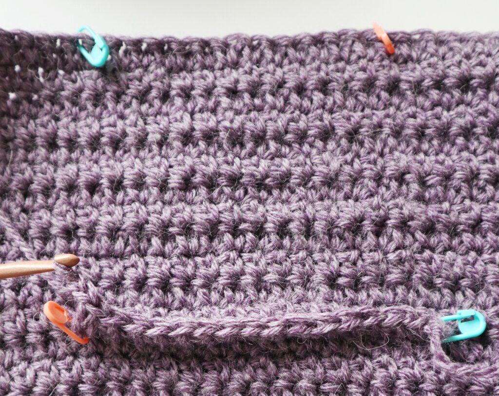 A swatch in purple yarn showing the construction of the crochet cardigan