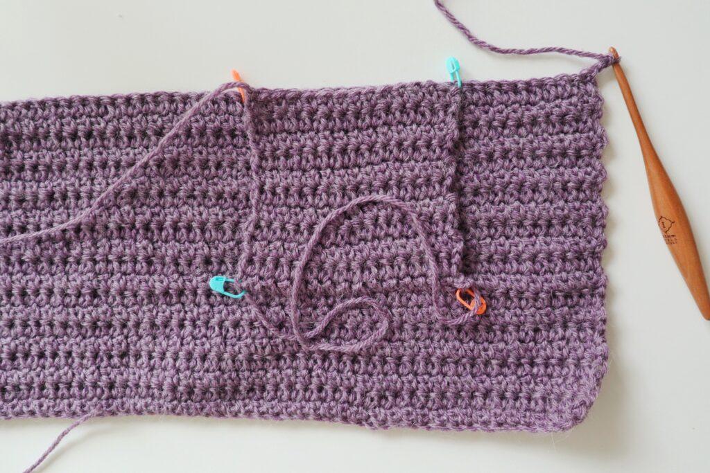 A swatch in purple yarn showing the construction of the crochet cardigan
