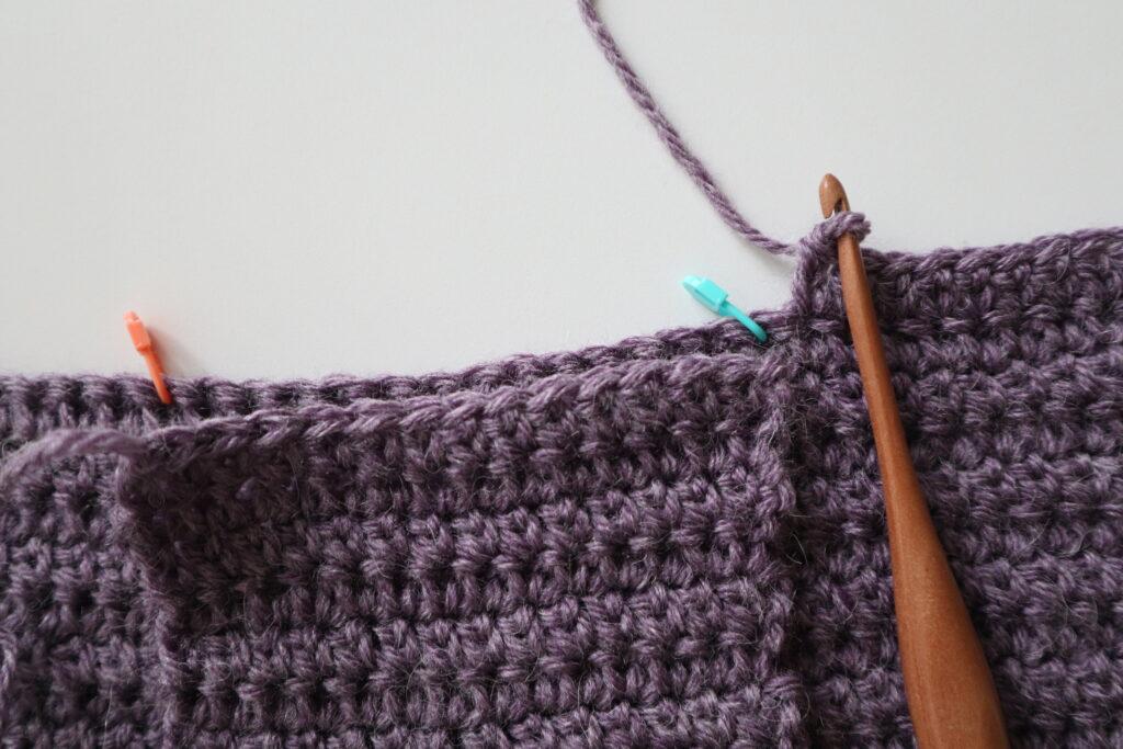 A swatch in purple yarn showing the construction of the crochet cardigan