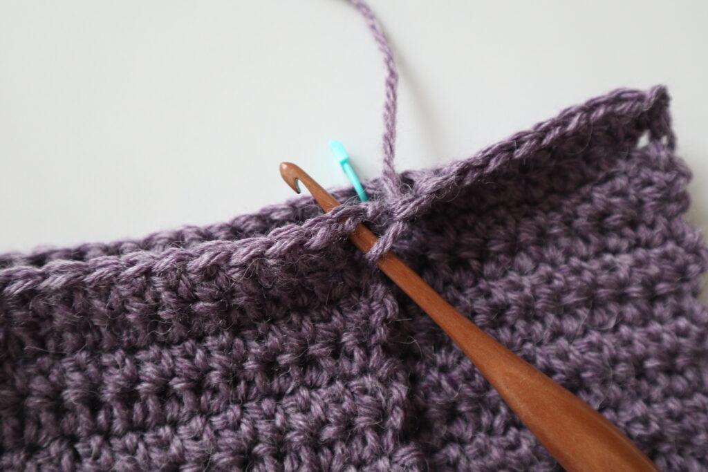 A swatch in purple yarn showing the construction of the crochet cardigan