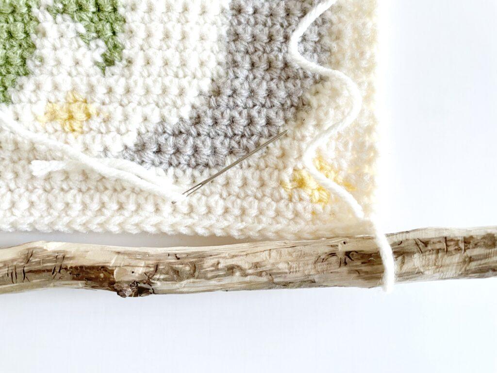 A tutorial graphic showing the placement of the stitch loops to attach the wall hanging to the wooden hanger.