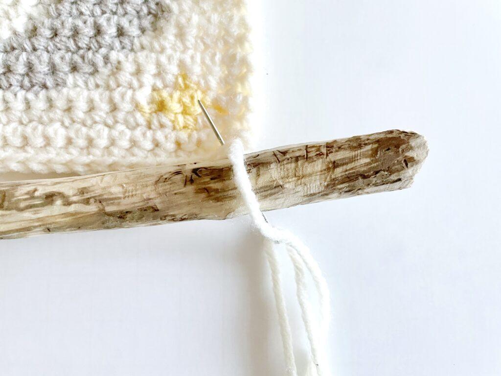 A tutorial graphic showing the placement of the stitch loops to attach the wall hanging to the wooden hanger.