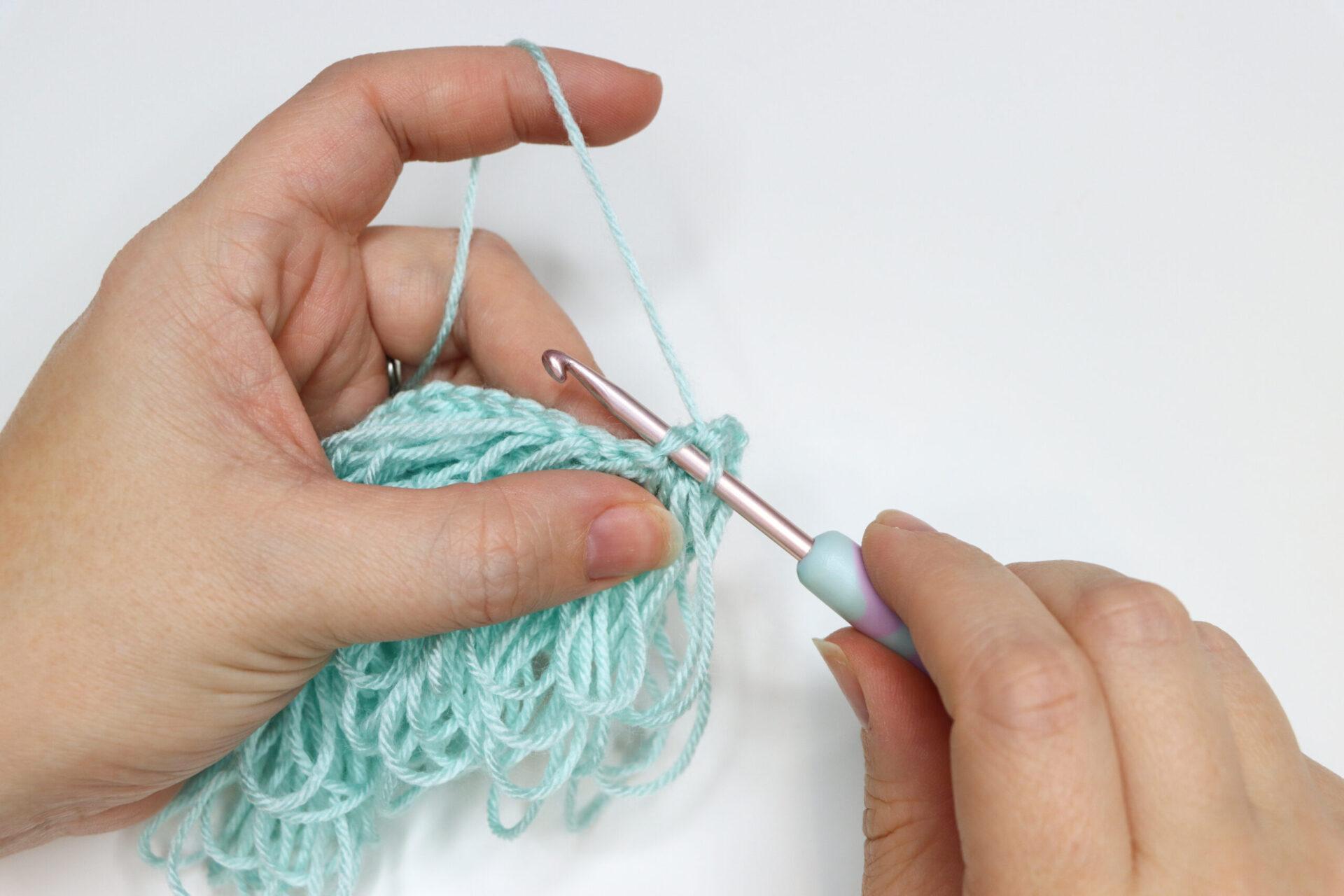 An in progress swatch of crocheted loop stitch in aqua yarn.