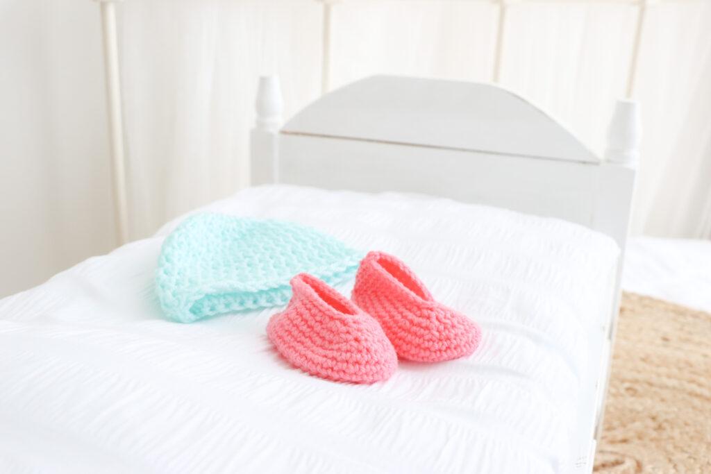 Crochet hat in light blue and booties in pink.
