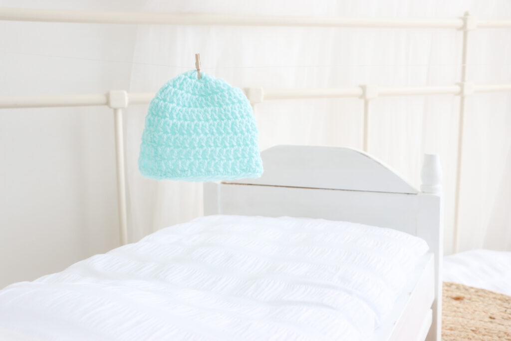 An aqua coloured baby beanie is pegged onto a white string.