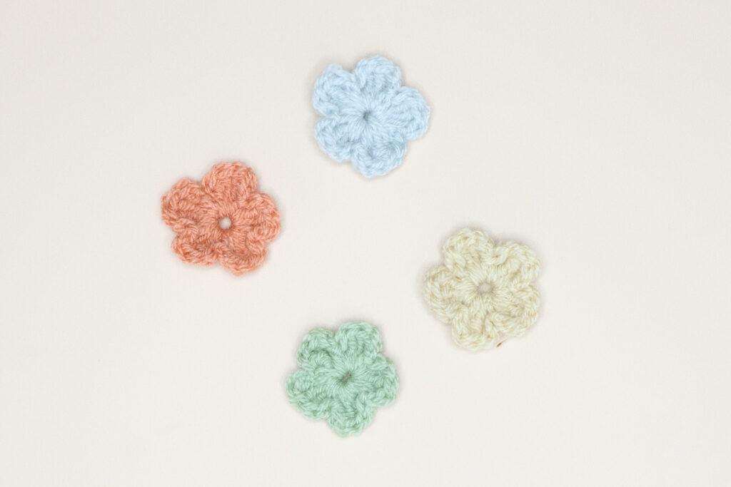 4 simple crochet flowers in light blue, Cream, Green and orange.