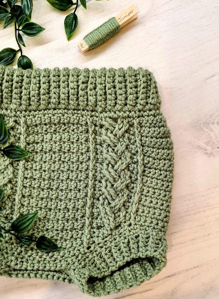 Childs crochet bloomers made in green yarn on a mable background