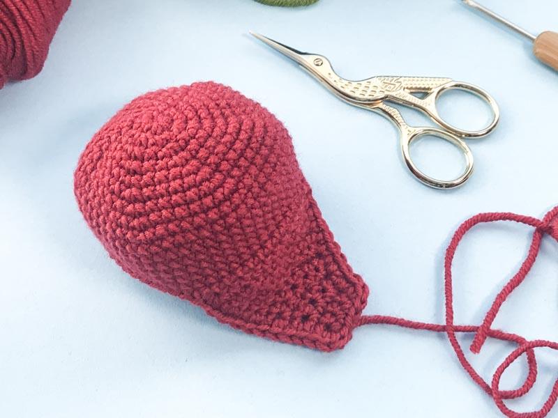 Red coloured yarn creating the face of the fox is show next to a pair of gold embroidery scissors.