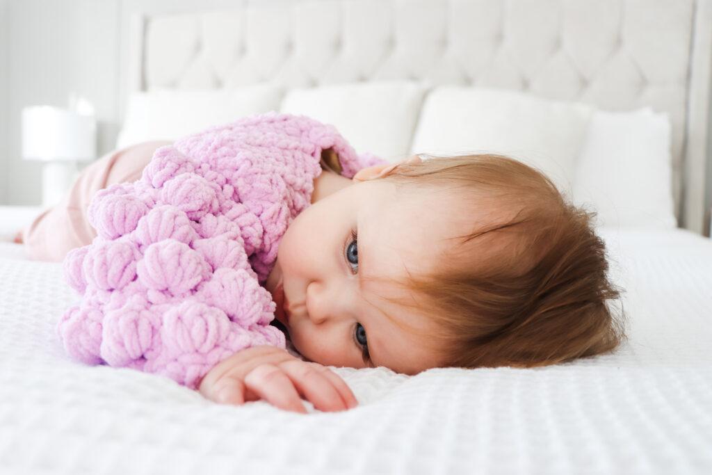 Baby girl in crochet bolero jacket with puff sleeves.
