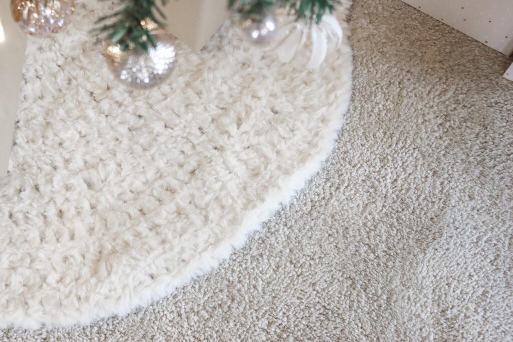 crochet tree skirt made from cream fluffy yarn shown around the base of a Christmas tree