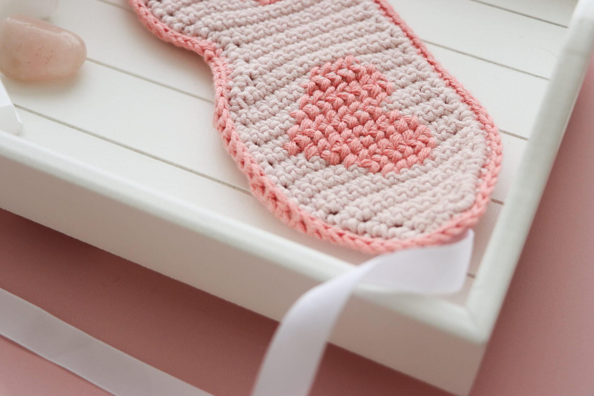 crochet sleep mask ob white tray alongside a pink candle and three crystals
