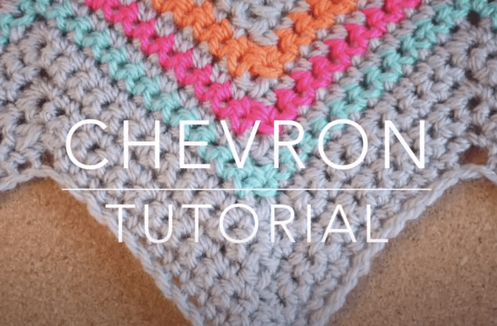 The chevron crochet stitch in grey yarn with blue, pink and orange chevron stripes. The crochet swatch lays on a wooden background and the words Chevron Tutorial are in white over the top.