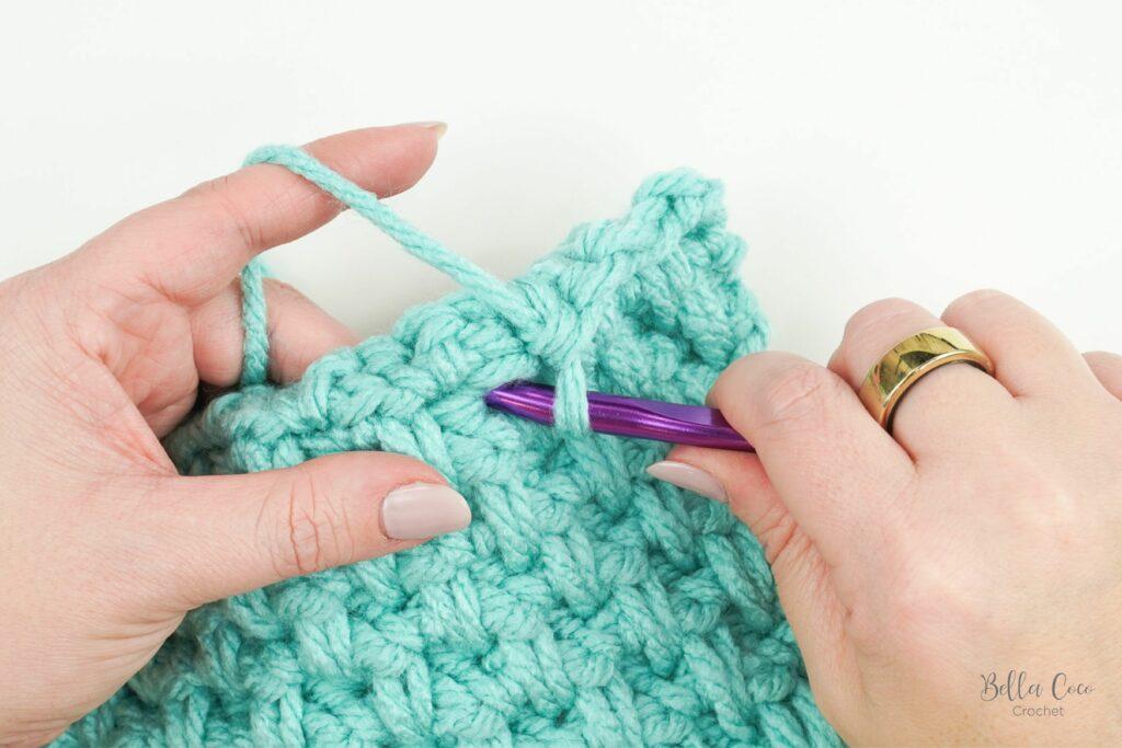 yarn swatch of honeycomb stitch using aqua yarn and purple crochet hook. image indicates where to insert hook