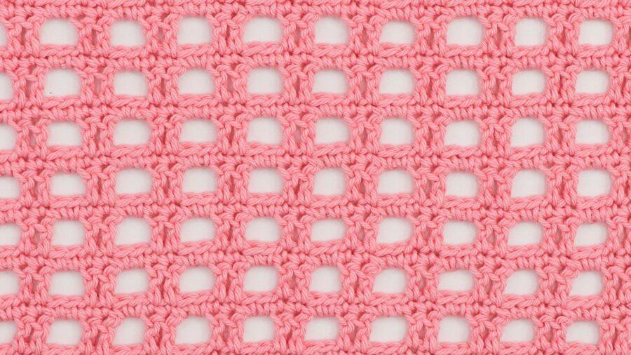 Pink crocheted mesh fabric with a square, openwork pattern