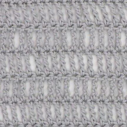Close-up of a crochet fabric made using the triple treble stitch, showing tall, elongated stitches in light gray yarn with visible vertical gaps for an airy, lacy texture.